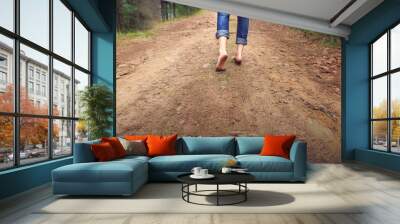 Person walking barefoot on gravel muddy road Wall mural