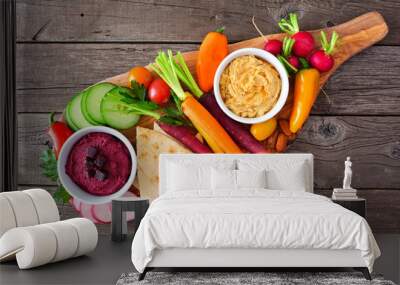 Assortment of fresh vegetables and hummus dip on a serving board. Top view on a rustic wood background. Wall mural