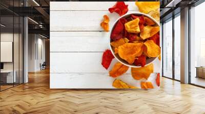 Bowl of mixed healthy vegetable chips. Top view, side orientation with copy space on a white wood background. Wall mural