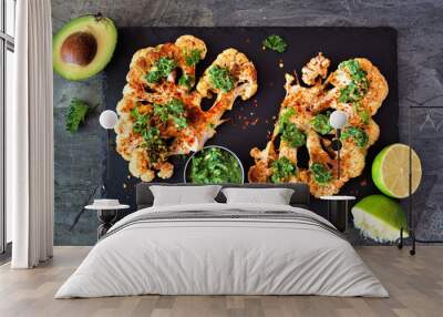 Cauliflower steaks with a cilantro lime sauce. Above view on a slate platter. Healthy eating, plant based meat substitute concept. Wall mural