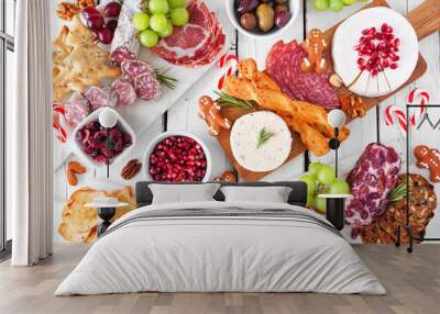 Christmas theme charcuterie table scene against a white wood background. Variety of cheese and meat appetizers. Above view. Wall mural