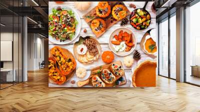 Delicious autumn meal table scene. Above view on a white wood background. Stuffed pumpkins and squash, sweet potatoes, appetizers, soup, vegetables and pumpkin pie. Wall mural