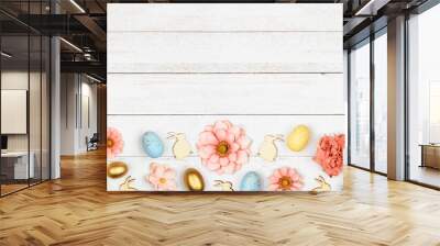 Easter bottom border with eggs, paper flowers and wooden bunnies. Top view against a white wood banner background. Copy space. Wall mural