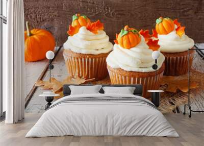 Fall pumpkin spice cupcakes with creamy frosting and autumn toppings. Close up against a rustic wood background. Wall mural