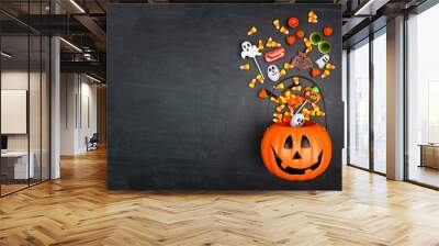 Halloween Jack o Lantern pail with spilling candy, top view on a black background with copy space Wall mural