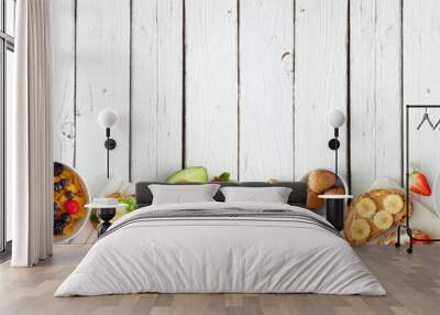 Healthy breakfast food banner with bottom border. Table scene with fruit, yogurt, smoothie bowl, nutritious toasts, cereal and egg skillet. Top view over a white wood background. Copy space. Wall mural