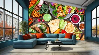 Healthy lunch table scene with nutritious Buddha bowl, lettuce wraps, vegetables, sandwiches and salad. Above view over a wood background. Wall mural