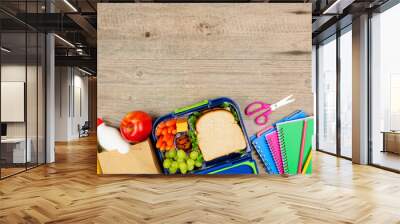 Healthy school lunch and school supplies. Top view bottom border on a wood background. Wall mural