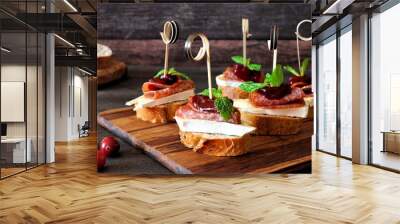 Holiday crostini skewers with cranberry sauce, brie, salami, and mint on a wooden server Wall mural