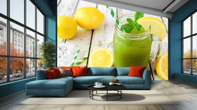 Iced matcha green tea lemonade in a mason jar glass with paper straw against a white wood background Wall mural