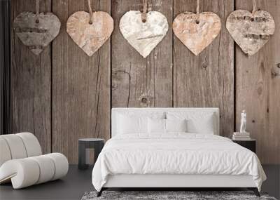 Rustic birch bark heart ornaments hanging against a vintage wooden background Wall mural