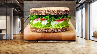 Superfood sandwich with avocado, egg whites, radish and pea shoots on whole grain bread against a rustic wood background Wall mural