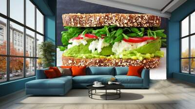 Superfood sandwich with whole grain bread, avocado, egg whites, radishes and pea shoots on marble against a black background Wall mural