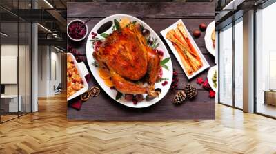 Traditional Christmas turkey dinner. Top view panoramic table scene on a dark wood banner background. Turkey, potatoes and sides, dressing, fruit cake and plum pudding. Wall mural