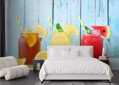 Variety of summer drinks in mason jar glasses with fruit against a blue wood background. Iced tea, lemonade and watermelon juice. Wall mural