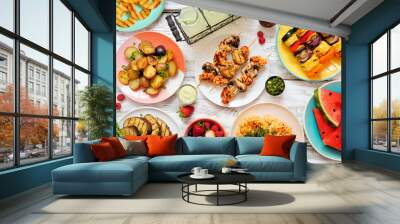 Vegan summer bbq or picnic table scene. Overhead view on a white wood background. Fruit, grilled vegetables, skewers, cauliflower steak and lemonade. Meat substitute concept. Wall mural