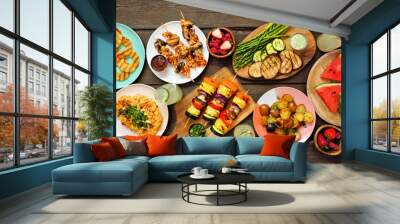 Vegan summer bbq or picnic table scene. Top view over a dark wood background. Grilled fruit and vegetables, skewers, cauliflower steak and vegetarian sides. Meat substitute concept. Wall mural