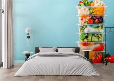 Stacked meal prep containers filled with fresh vegetables and fruits, light background. Wall mural