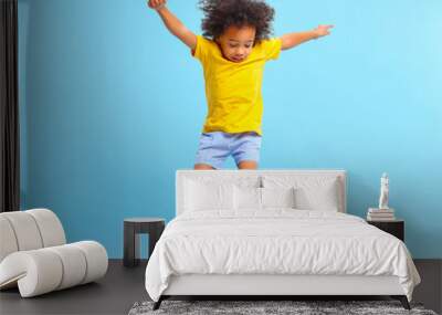 Active black kid jumping against blue background Wall mural