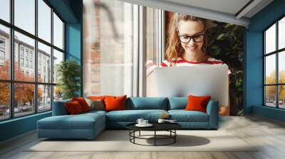 Calm young woman   working on laptop at home. Wall mural