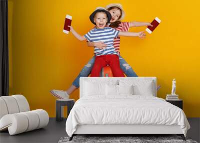 cheerful children boy and girl travelers with suitcase on colored yellow background. Wall mural