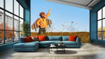 Child pilot aviator with wings of airplane dreams of traveling in summer  at sunset Wall mural