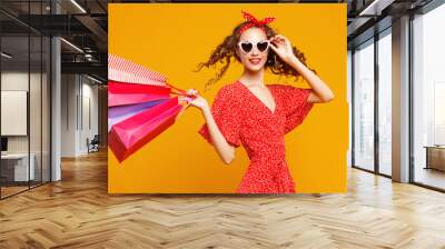 concept of shopping purchases and sales of happy   girl with packages  on yellow background. Wall mural