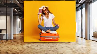 concept of travel. happy woman girl with suitcase and  passport on  yellow background. Wall mural