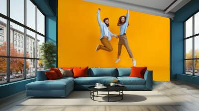 couple of emotional people man and woman jumping on yellow background. Wall mural