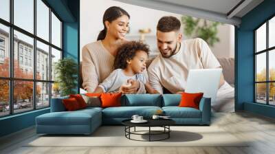 Diverse family using laptop on sofa together. Wall mural