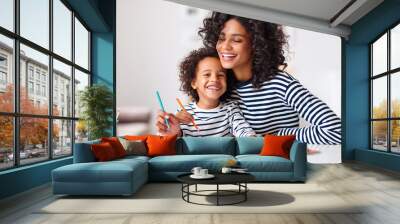 Excited ethnic mother and son doing homework Wall mural