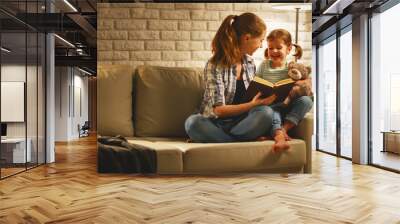 Family before going to bed mother reads to child daughter book near lamp in the evening. Wall mural