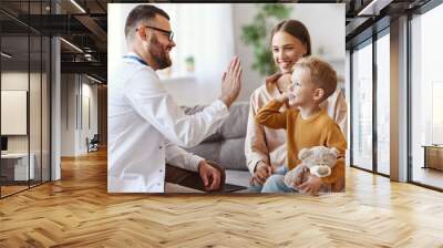 family doctor pediatrician conducts examination of   child boy and giving high five to him  . Wall mural