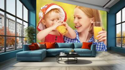 family mother and baby daughter drinking orange juice in the sum Wall mural