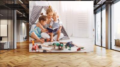 family mother reading to children book in tent at home. Wall mural