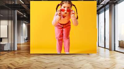 funny funny child girl in pink clothes on yellow background Wall mural