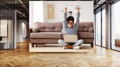 glad woman celebrating good news while working on laptop at home Wall mural