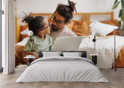 Happy african american family little son with dad watching funny videos on laptop together at home Wall mural