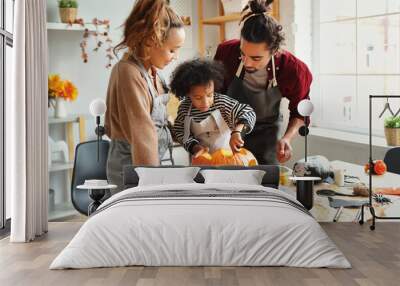 Happy african american family mother, father and child son carving pumpkin for Halloween holiday together at home Wall mural