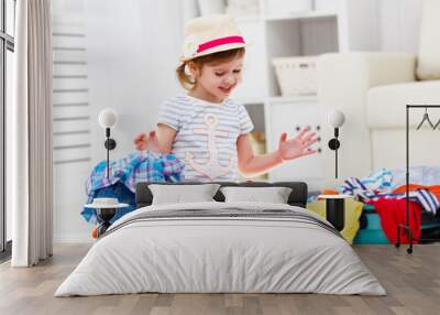 happy child girl packs clothes into suitcase for travel, vacatio Wall mural