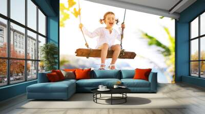 Happy child girl swinging on swing at beach  in summer Wall mural