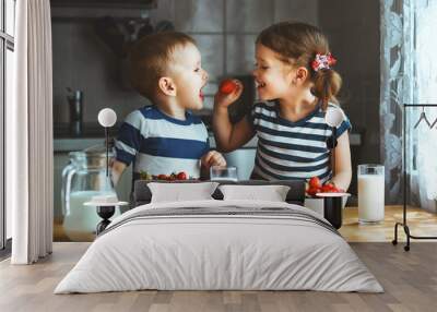 Happy children brother and sister eating strawberries with milk Wall mural