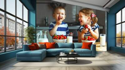 Happy children brother and sister eating strawberries with milk Wall mural