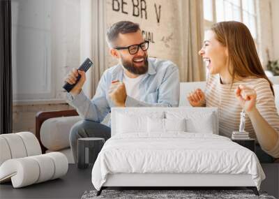 Happy couple celebrating victory while watching TV Wall mural