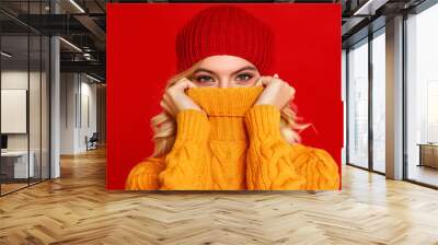 happy emotional cheerful girl laughing  with knitted autumn cap  on colored red background Wall mural