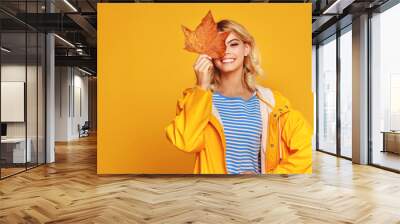 happy emotional girl with autumn leaves on colored yellow background. Wall mural