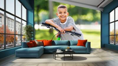 happy ethnic boy riding bike in park in summer Wall mural