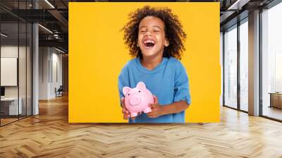 Happy ethnic boy storing money in piggy bank Wall mural