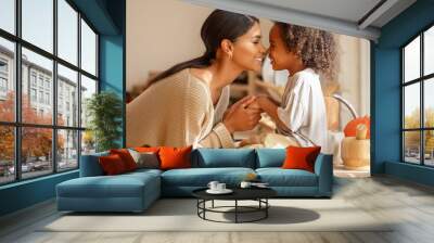 Happy ethnic family mother and   son kiss and laugh in the kitchen at home. Wall mural