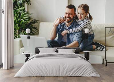 happy family a businessman father working at a computer and his child daughter  at home. Wall mural